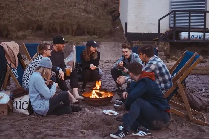 menschen sitzen um ein lagerfeuer und reden