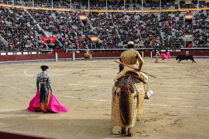 Stierkampfarena mit Menschen auf den Raengen und Matadoren in der Arena.