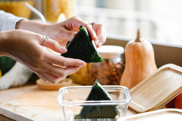 Eine Person legt Onigiri in eine Glasdose.