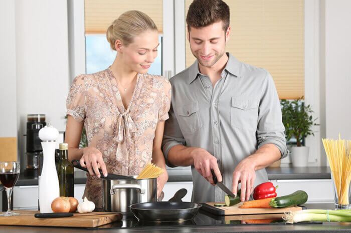 Eine Frau und ein Mann stehen am Herd und kochen.